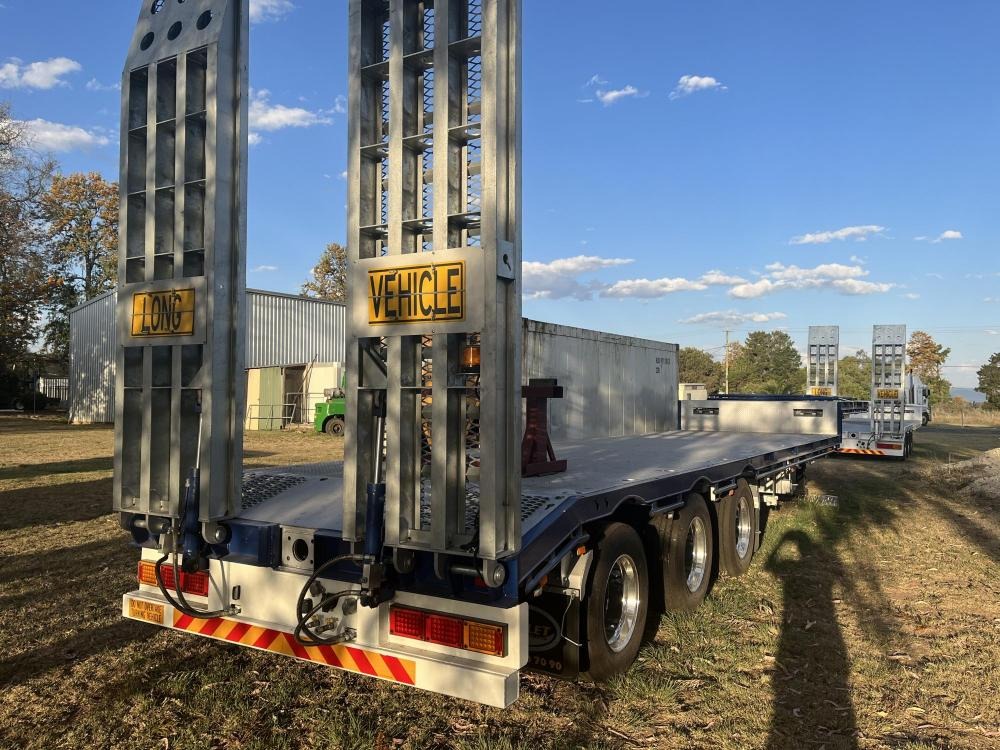 A white drop deck trailer in a yard